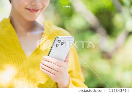 A woman using a smartphone outdoors. 115843714