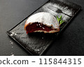 An appetizing donut with strawberries sprinkled with powdered sugar on a black rectangular plate on a gray background 115844315
