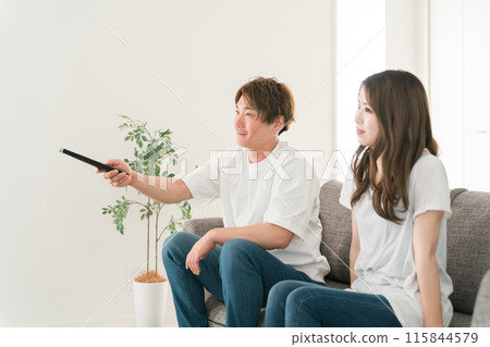 Young Japanese family watching TV on the sofa at home (remote control) 115844579