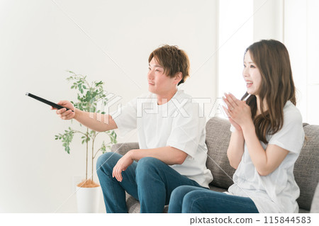 Young Japanese family watching TV on the sofa at home (remote control) 115844583