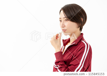 Woman in a jersey blowing a whistle Woman in a jersey blowing a whistle 115845153