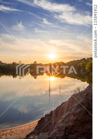 The serene lake shows a beautiful sunset, creating a calming view of natures tranquility The serene lake shows a beautiful sunset, creating a calming view of natures tranquility 115845912