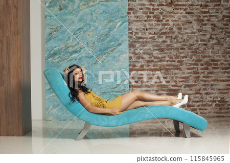 Attractive young woman make-up and long hair wearing yellow dress posing sitting Attractive young woman make-up and long hair wearing yellow dress posing sitting 115845965