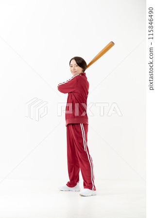 一個穿著球衣的女人揮舞著球棒 115846490