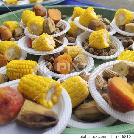 A dessert dish at an event consisting of boiled corn, boiled keledek, and boiled banana served on a plastic plate. 115846810