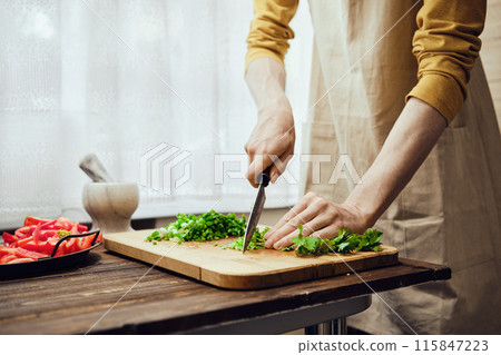 Chopping cilantro with kitchen knife in the kitchen Chopping cilantro with kitchen knife in the kitchen 115847223