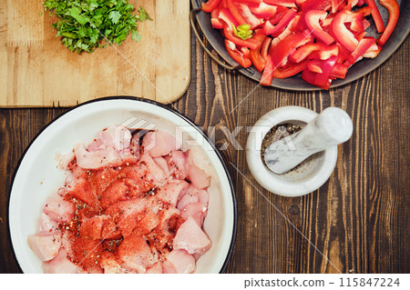 Top view of kitchen table with copped chicken fillet, bell pepper and cilantro Top view of kitchen table with copped chicken fillet, bell pepper and cilantro 115847224