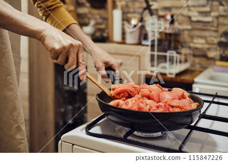 Unrecognizable man stirring chopped chicken fillet in frying pan with spatula Unrecognizable man stirring chopped chicken fillet in frying pan with spatula 115847226