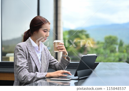 Attractive businesswoman enjoying a cup of coffee and using digital tablet at building terrace Attractive businesswoman enjoying a cup of coffee and using digital tablet at building terrace 115848537