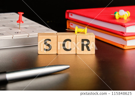Text SCR word is made up of wooden cubes on a black background in a concept with business accessories Text SCR word is made up of wooden cubes on a black background in a concept with business accessories 115848625