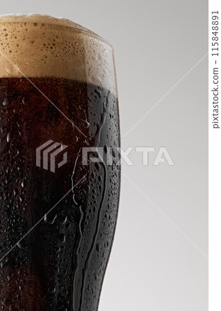 Pint of dark beer with creamy head. Condensation droplets on glass emphasize coolness and freshness of stout. Pint of dark beer with creamy head. Condensation droplets on glass emphasize coolness and freshness of stout. 115848891