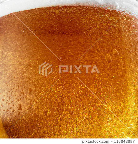 Cold beer in glass with condensation droplets. Bright golden color and lighting make drink look appealing and refreshing. Cold beer in glass with condensation droplets. Bright golden color and lighting make drink look appealing and refreshing. 115848897