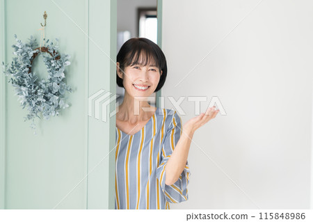 A middle-aged woman welcoming guests at the entrance A middle-aged woman welcoming guests at the entrance 115848986