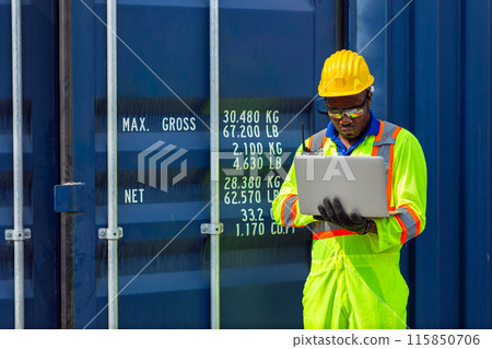 African Black Worker in Cargo Port Shipping Industrial in Yellow Hard Hat Safety Vest on Duty. Foreman or Supervisor in Container Ship Yard Terminal. 115850706