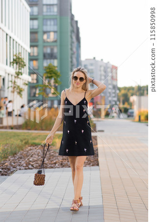 Happy young Caucasian girl in sunglasses walking in the city on a sunny day 115850998