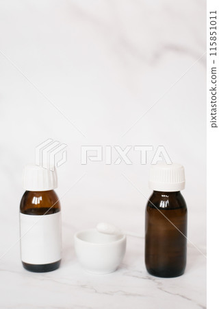 On the table next to the bowl and a cotton swab are two glass bottles for face peeling in the cosmetologist's office 115851011