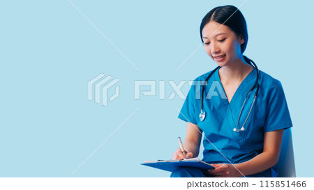 Medical assistant. Healthcare consulting. Cheerful doctor woman in uniform writing diagnosis taking notes on clipboard isolated on blue empty space background. Medical assistant. Healthcare consulting. Cheerful doctor woman in uniform writing diagnosis taking notes on clipboard isolated on blue empty space background. 115851466