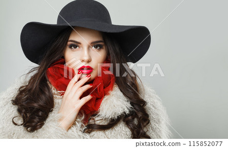 Cute young adult woman fashion model with bright make-up and long wavy hair wearing blue hat posing Cute young adult woman fashion model with bright make-up and long wavy hair wearing blue hat posing 115852077