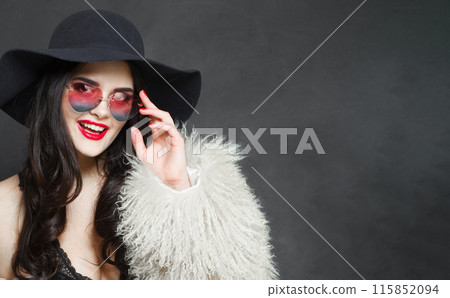 Laughing young adult woman fashion model with bright make-up and long wavy hair wearing blue hat Laughing young adult woman fashion model with bright make-up and long wavy hair wearing blue hat 115852094