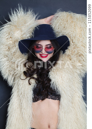 Happy young adult woman fashion model with bright make-up and long wavy hair wearing blue hat Happy young adult woman fashion model with bright make-up and long wavy hair wearing blue hat 115852099