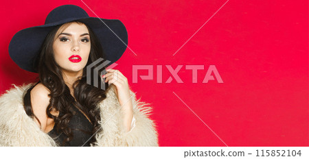 Beautiful young adult woman fashion model with bright make-up and long wavy hair wearing blue hat Beautiful young adult woman fashion model with bright make-up and long wavy hair wearing blue hat 115852104
