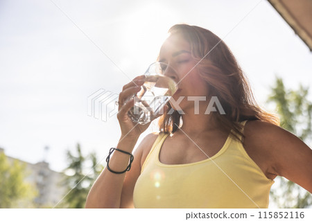 Dehydrated woman drinks clean water from a glass to replenish fluids during hot summer days Dehydrated woman drinks clean water from a glass to replenish fluids during hot summer days 115852116