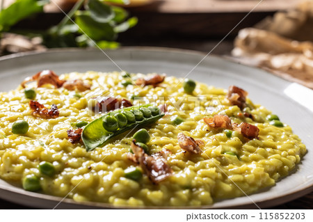 Italian saffron risotto with peas and bacon creatively served on a plate 115852203