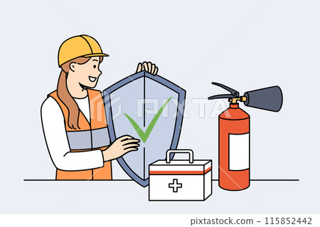 Woman safety specialist, stands near table with first aid kit and fire extinguisher and holds shield 115852442