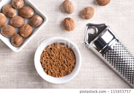 Nutmeg powder, ground nutmeg in a small white bowl on linen fabric. Fragrant or true nutmeg, a spice, also used in traditional medicine. With dried seeds of Myristica fragrans and a nutmeg grater. Nutmeg powder, ground nutmeg in a small white bowl on linen fabric. Fragrant or true nutmeg, a spice, also used in traditional medicine. With dried seeds of Myristica fragrans and a nutmeg grater. 115853757