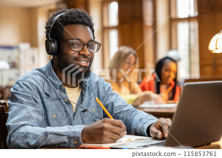 African american young man in headphones working on laptop 115853761