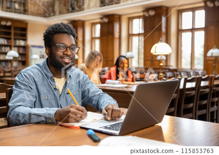 African american young man in headphones working on laptop 115853763