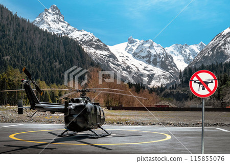 Helicopter landed on the base on the helipad in the mountains. No fly zone sign prohibiting flights of drones. No drone zone concept 115855076