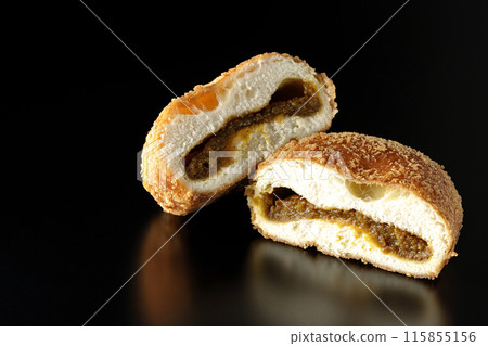 Curry bread cut in half photographed against a black background Curry bread cut in half photographed against a black background 115855156