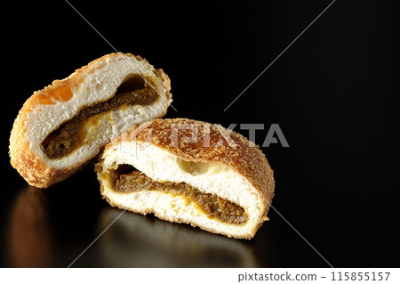 Curry bread cut in half photographed against a black background Curry bread cut in half photographed against a black background 115855157