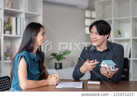 Real Estate Agent Discussing Property Sale Contract with Client in Modern Office Setting 115855225