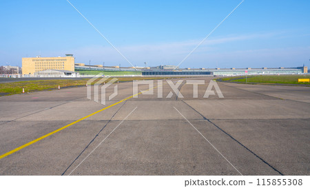 Clear blue skies over the historic Berlin Tempelhof Airport in Germany, showcasing the vast airport tarmac and iconic terminal building with hangars. Clear blue skies over the historic Berlin Tempelhof Airport in Germany, showcasing the vast airport tarmac and iconic terminal building with hangars. 115855308
