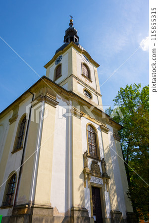 A low-angle view of Saint Lawrence Church in Potstejn, Czechia, showcasing the churchs facade, bell tower, and a sign reading Charitas. A low-angle view of Saint Lawrence Church in Potstejn, Czechia, showcasing the churchs facade, bell tower, and a sign reading Charitas. 115855315