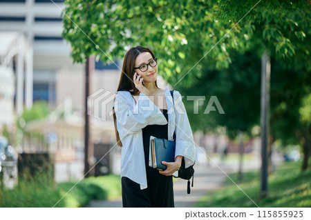 年輕女子一邊走路一邊用智慧型手機打電話 年輕女子一邊走路一邊用智慧型手機打電話 115855925