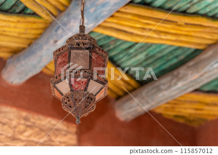 Old ancient Moroccan lantern hanging from a traditionally built wooden ceiling, Agadir Old ancient Moroccan lantern hanging from a traditionally built wooden ceiling, Agadir 115857012