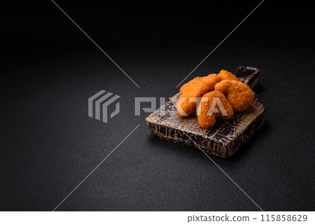 Delicious fresh crispy chicken nuggets on a dark concrete background 115858629