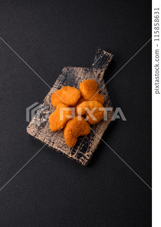 Delicious fresh crispy chicken nuggets on a dark concrete background Delicious fresh crispy chicken nuggets on a dark concrete background 115858631