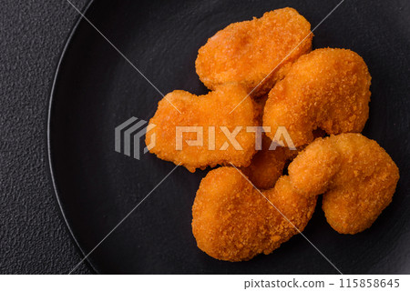 Delicious fresh crispy chicken nuggets on a dark concrete background Delicious fresh crispy chicken nuggets on a dark concrete background 115858645