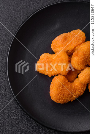 Delicious fresh crispy chicken nuggets on a dark concrete background Delicious fresh crispy chicken nuggets on a dark concrete background 115858647