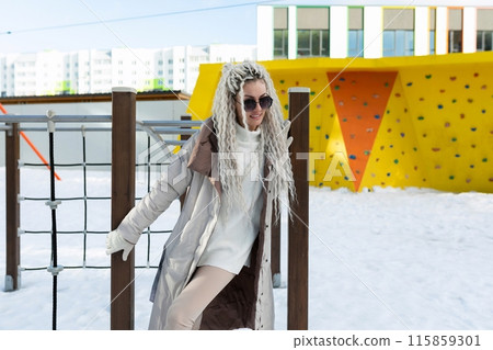 Woman in White Coat and Sunglasses Standing in Snow 115859301