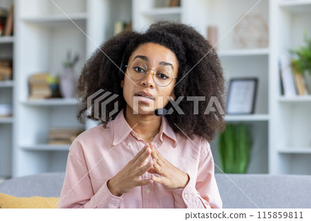 Confident woman wearing glasses and headset speaking during video call. Modern office. Concept of remote work, online meeting, communication, consulting, customer support, and virtual interaction. Confident woman wearing glasses and headset speaking during video call. Modern office. Concept of remote work, online meeting, communication, consulting, customer support, and virtual interaction. 115859811