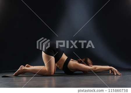 girl doing yoga and stretching, yoga and stretching poses on a dark background, yoga practice 115860738