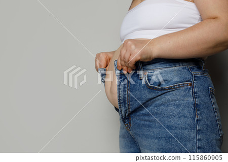 Female person trying to zip up her denim pants on white background, dieting concept 115860905