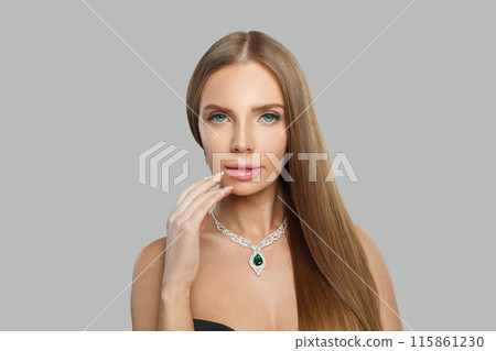 Posing woman with makeup wearing jewelry necklace with sapphire and diamond on grey background Posing woman with makeup wearing jewelry necklace with sapphire and diamond on grey background 115861230