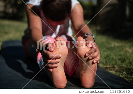 Woman practicing yoga outdoors stretching legs on mat 115861680
