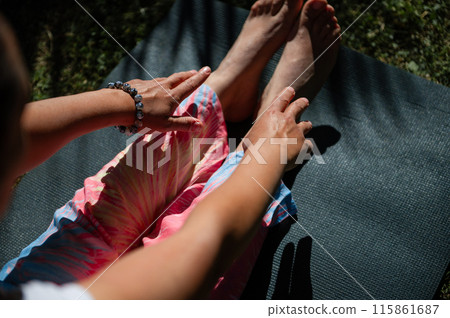 Woman practicing yoga outdoors on a mat during a sunny day 115861687